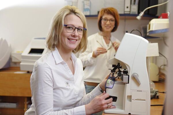 Zwei Optikerinnen prüfen Brillengläser mit moderner Messtechnik im Optikerfachgeschäft.